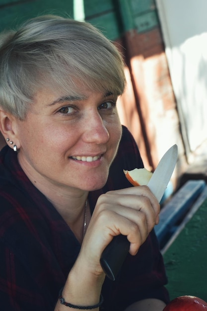 Photo portrait of a smiling young woman holding a peace of fruit