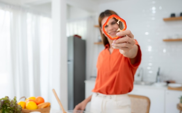 Portrait of smiling young woman holding a red chili in her hands at home