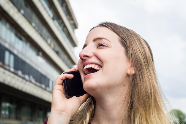 Portrait of smiling young woman holding smart phone outdoors