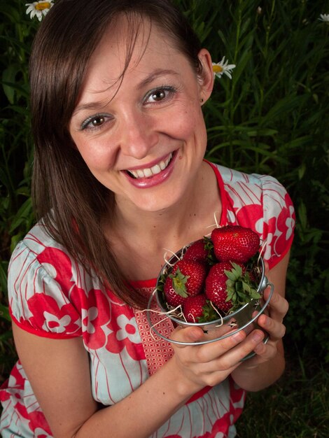 イチゴを持って笑顔の若い女性の肖像画。