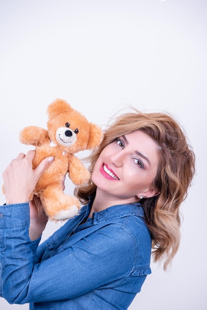 Foto ritratto di una giovane donna sorridente che tiene un giocattolo di peluche su uno sfondo bianco