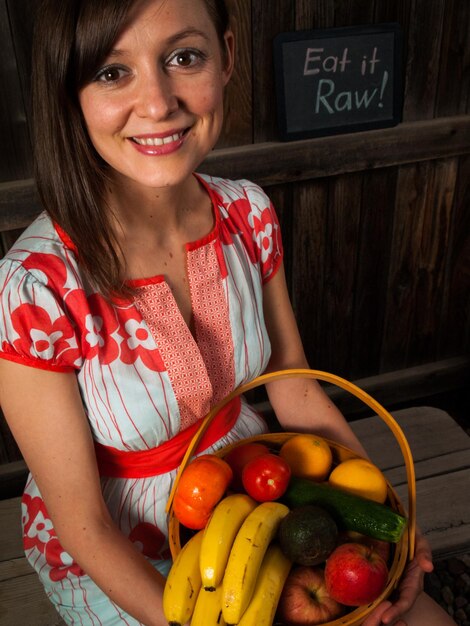 Portrait of a smiling young woman holding vegetables in basket.