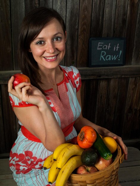 バスケットに野菜を保持している笑顔の若い女性の肖像画。