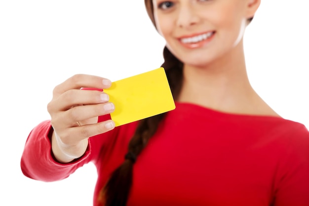 Portrait of smiling young woman holding yellow card against white background