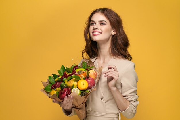 Portrait of smiling young woman holding yellow flowers against orange background