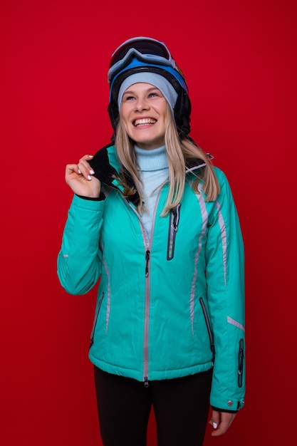 Portrait of a smiling young woman in a jacket helmet and ski\
goggles