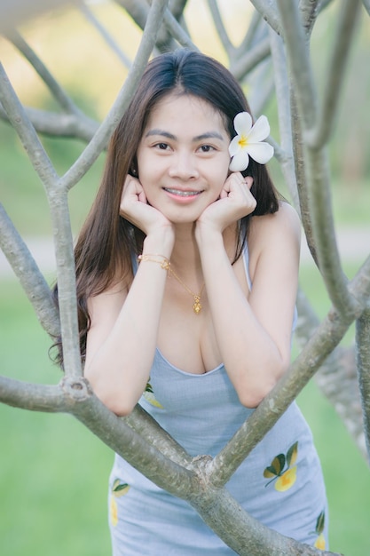 Photo portrait of smiling young woman leaning on tree