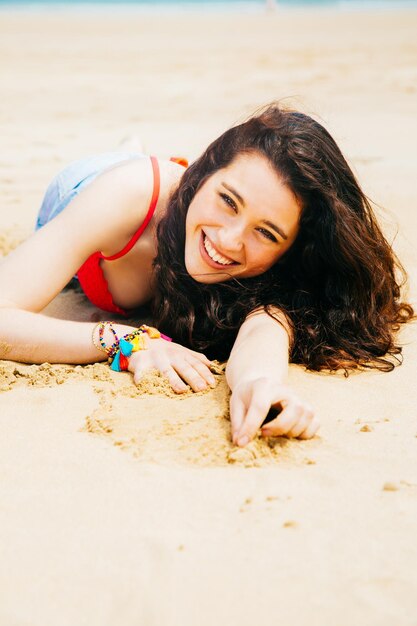Photo portrait of smiling young woman lying on beach
