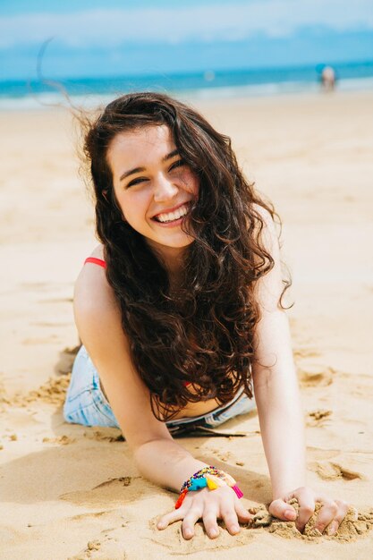 portrait of smiling young woman lying on beach