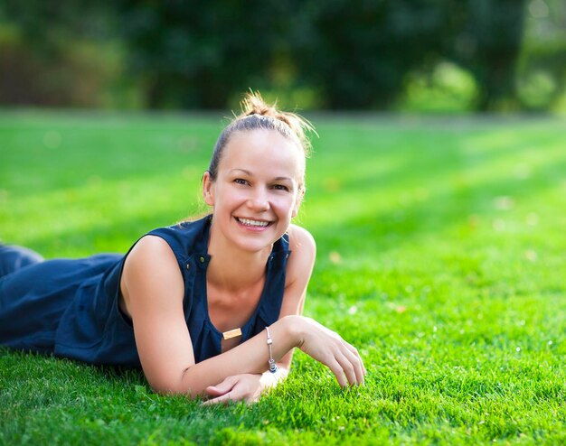 Portrait of smiling young woman lying on grass