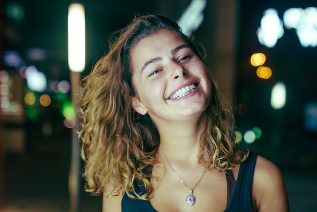 Photo portrait of smiling young woman at night