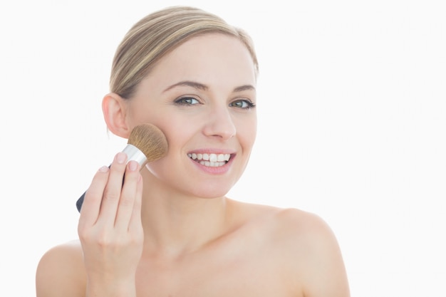 Portrait of smiling young woman putting on makeup