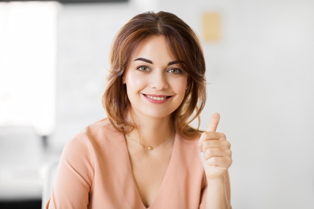 Photo portrait of smiling young woman showing thumbs up