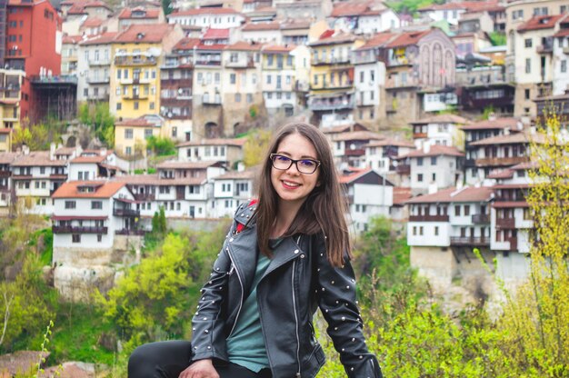 Portrait of smiling young woman sitting against townscape