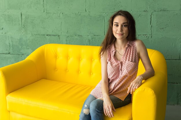 Portrait of a smiling young woman sitting against wall