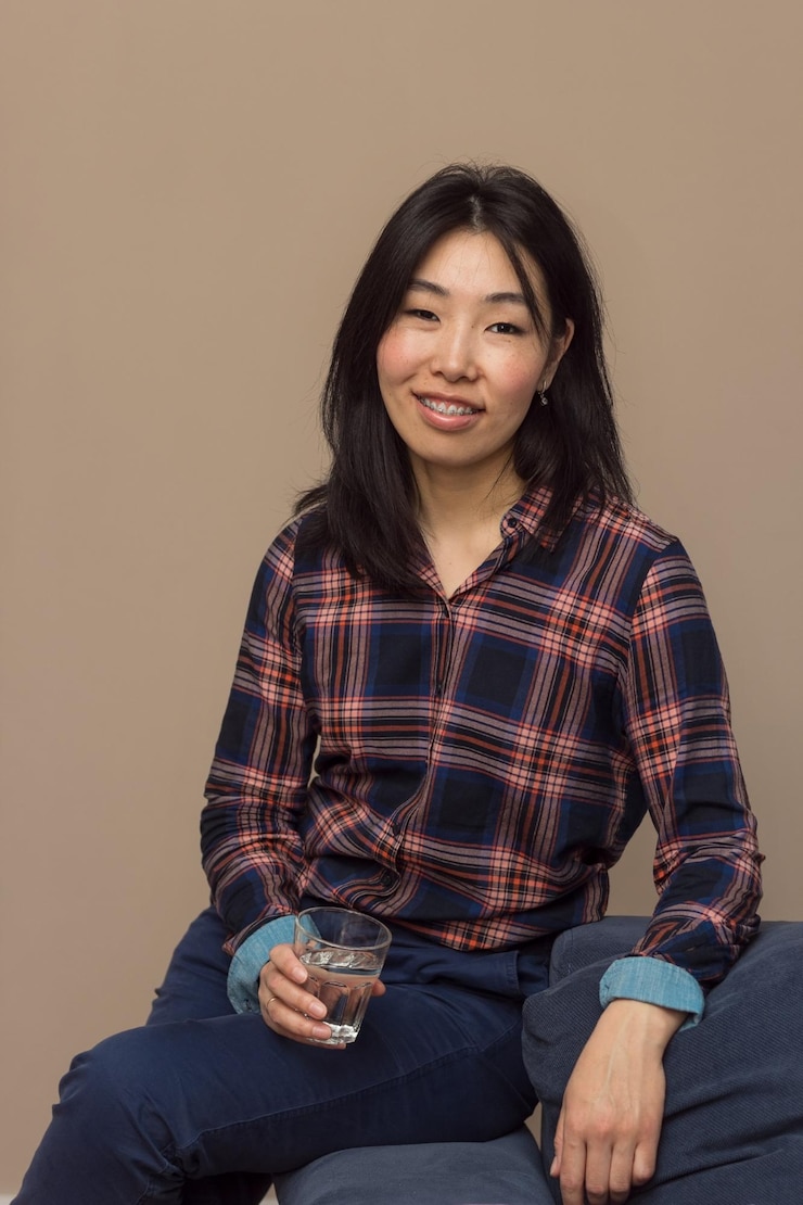 Photo 壁に寄りかかって座っている笑顔の若い女性の肖像画