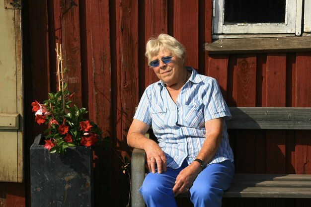 Photo portrait of smiling young woman sitting against wall