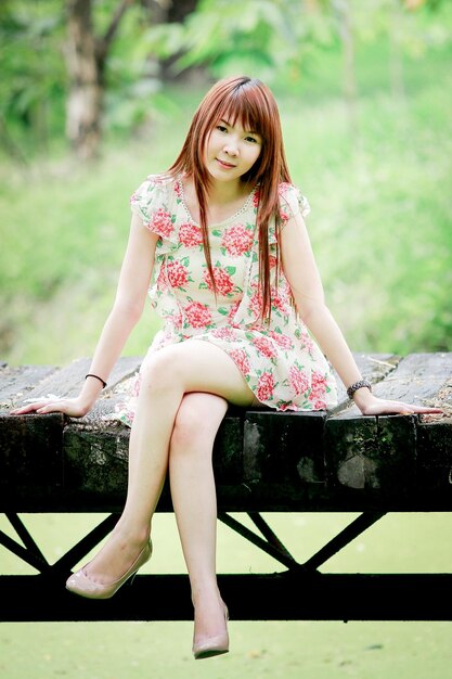 Portrait of smiling young woman sitting on bridge