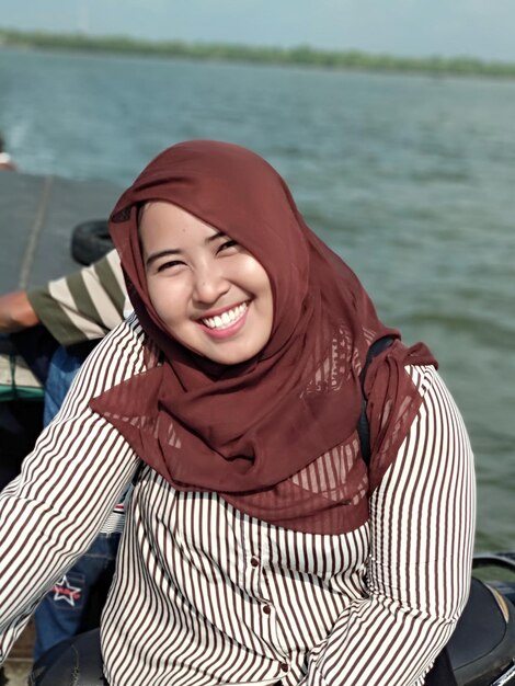 Photo portrait of smiling young woman sitting by sea