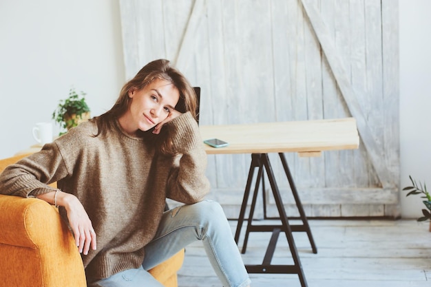Portrait of smiling young woman sitting on chair at home