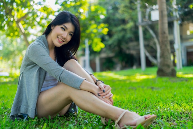 Photo portrait of smiling young woman sitting on field against trees