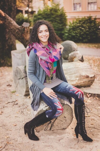 Photo portrait of smiling young woman sitting on logs