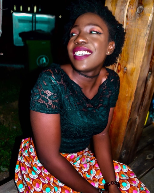 Photo portrait of smiling young woman sitting outdoors