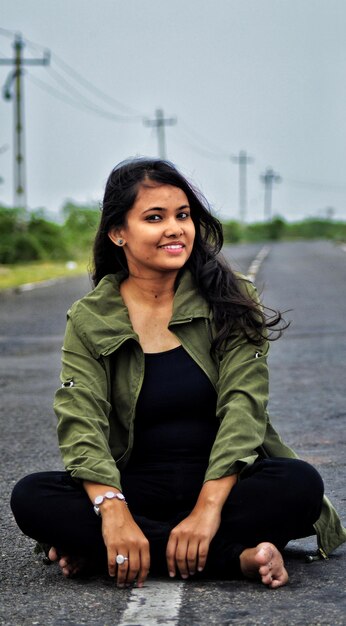 Photo portrait of smiling young woman sitting road