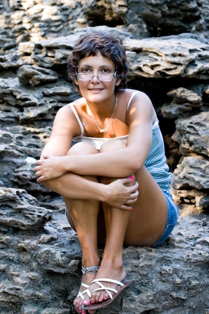 Photo portrait of smiling young woman sitting on rock