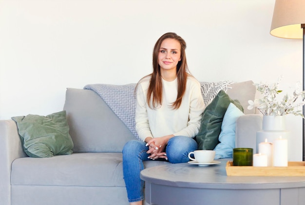 Portrait of smiling young woman sitting on sofa at home