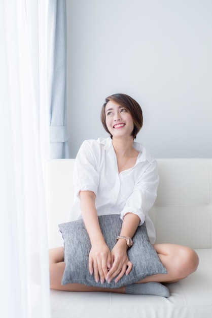 Portrait of smiling young woman sitting on sofa at home