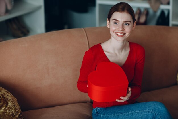 Photo portrait of a smiling young woman sitting on sofa