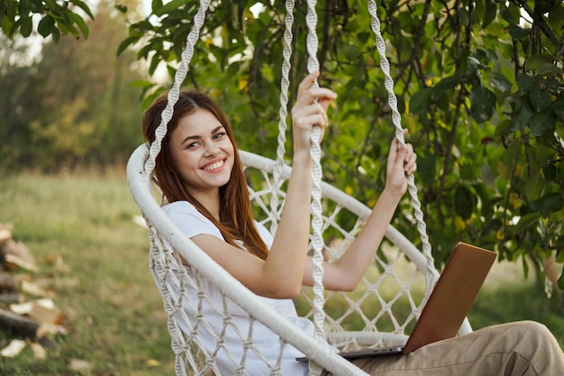 Foto ritratto di una giovane donna sorridente seduta su un'altalena nel parco