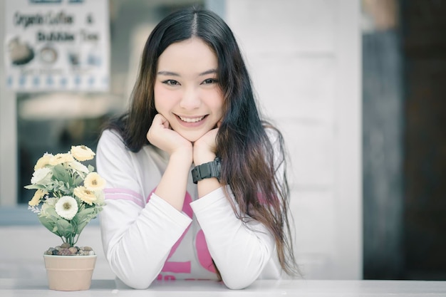 街のテーブルに座っている笑顔の若い女性の肖像画