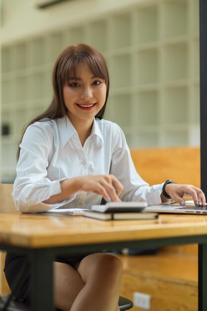 Photo portrait of a smiling young woman sitting on table