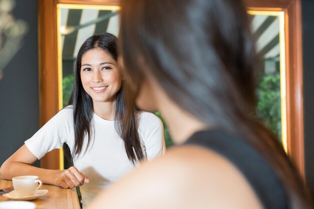 Photo portrait of a smiling young woman sitting on table