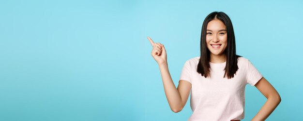 Portrait of smiling young woman standing against blue background