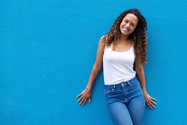 Portrait of smiling young woman standing against blue wall