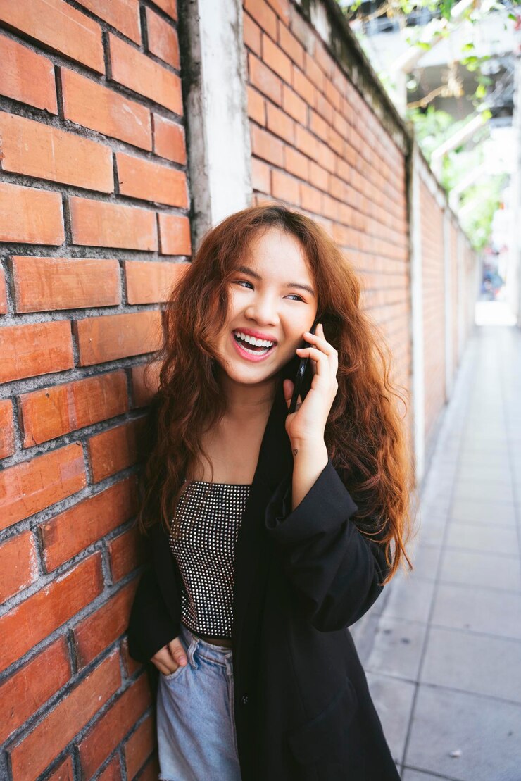 Photo レンガの壁に立っている笑顔の若い女性の肖像画