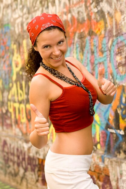 Photo portrait of a smiling young woman standing against graffiti wall