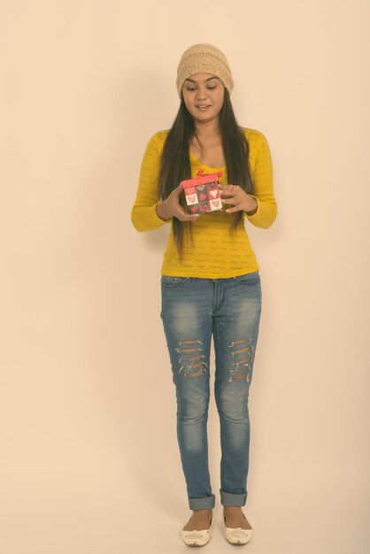 Portrait of smiling young woman standing against gray background