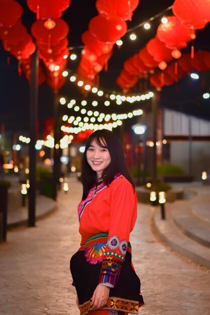 Photo portrait of smiling young woman standing against illuminated lights at night