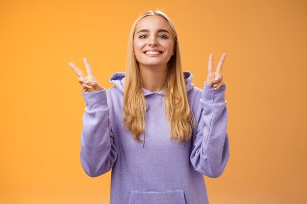 Portrait of smiling young woman standing against orange background