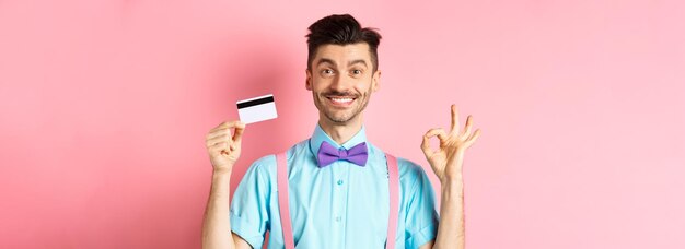 Portrait of smiling young woman standing against pink background