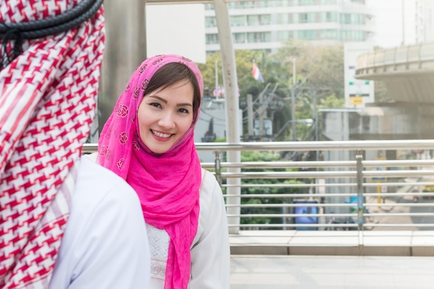 Photo portrait of smiling young woman standing against pink outdoors