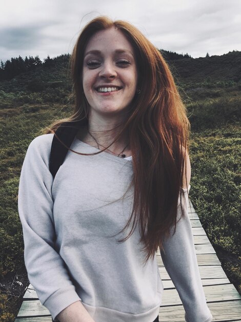 Portrait of smiling young woman standing against plants