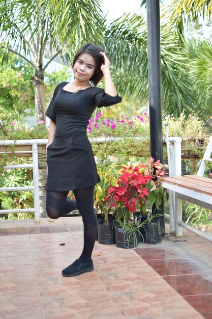 Portrait of smiling young woman standing against plants