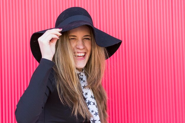 Foto ritratto di una giovane donna sorridente in piedi contro un muro rosso