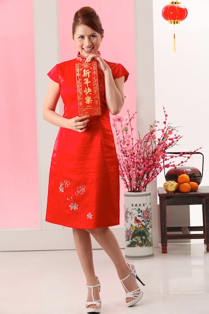 Photo portrait of a smiling young woman standing against red wall