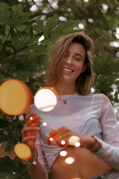 Foto ritratto di una giovane donna sorridente in piedi contro gli alberi